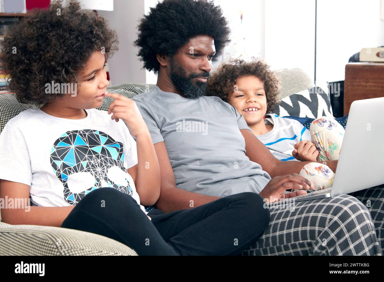 La famiglia si diverte con il laptop sul divano Foto Stock