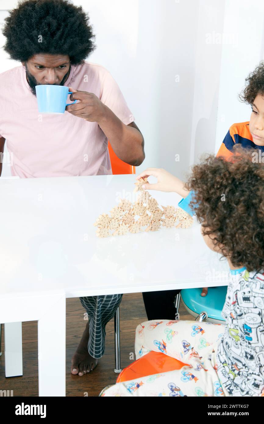 Genitori che guardano il bambino giocare con il cibo a tavola Foto Stock