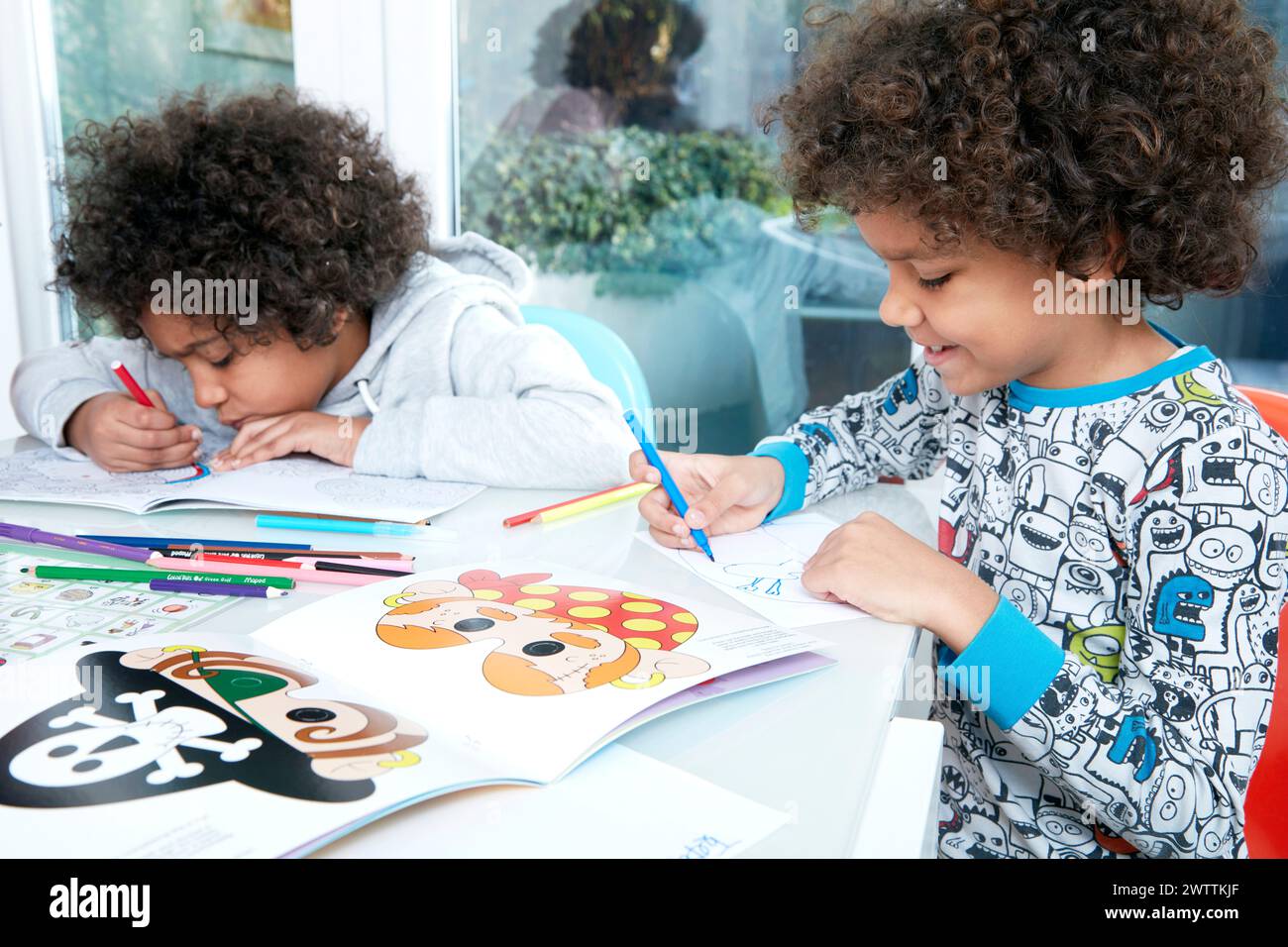 Due bambini che colorano libri di attività a un tavolo Foto Stock