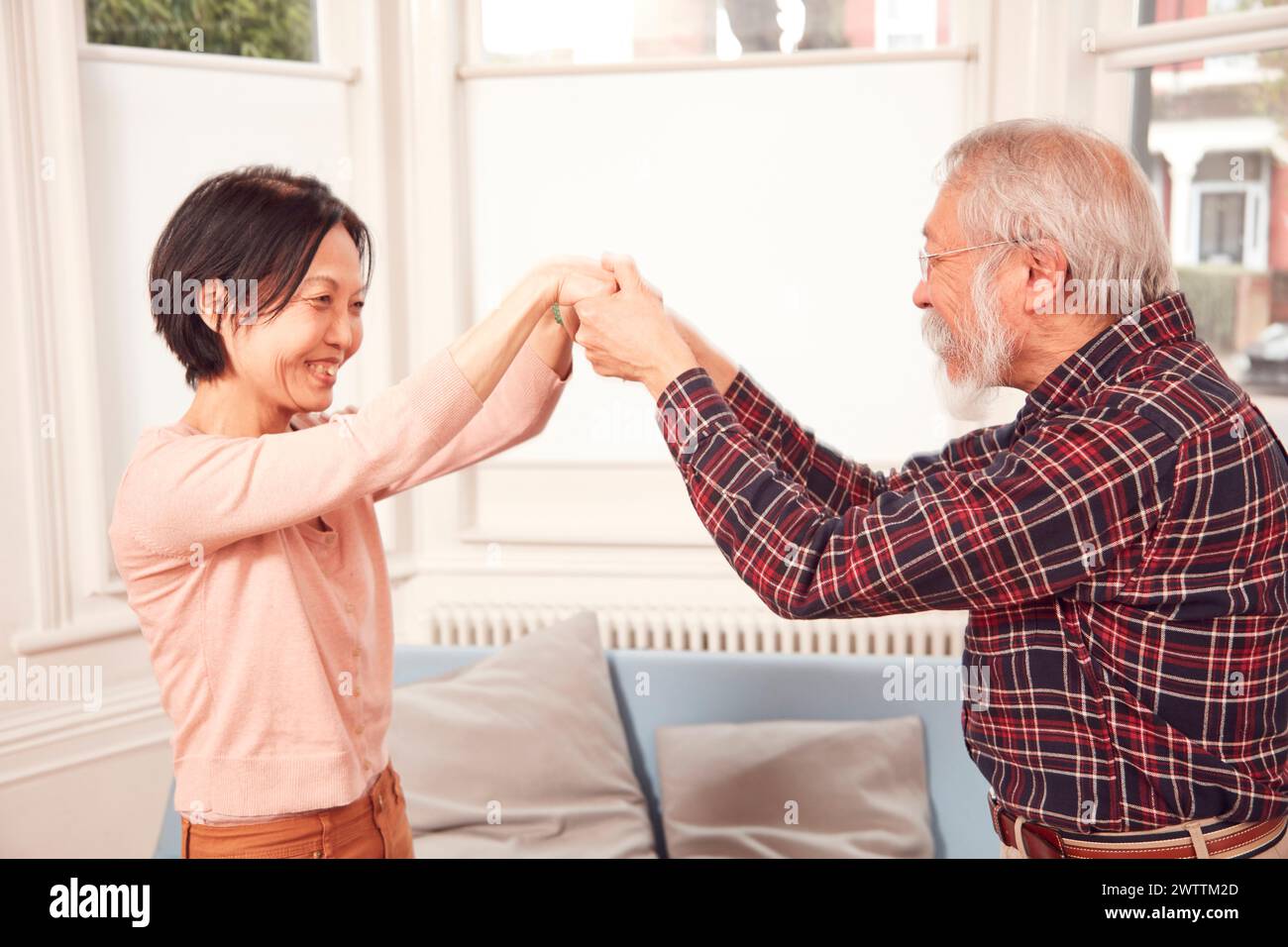 Due persone sorridenti e tenute per mano in casa Foto Stock