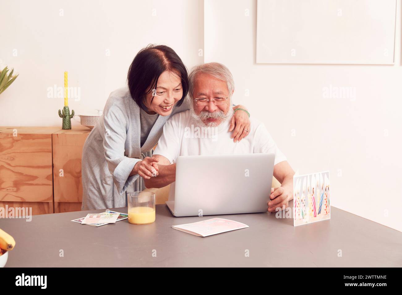 Una coppia di anziani sorride e guarda un notebook Foto Stock