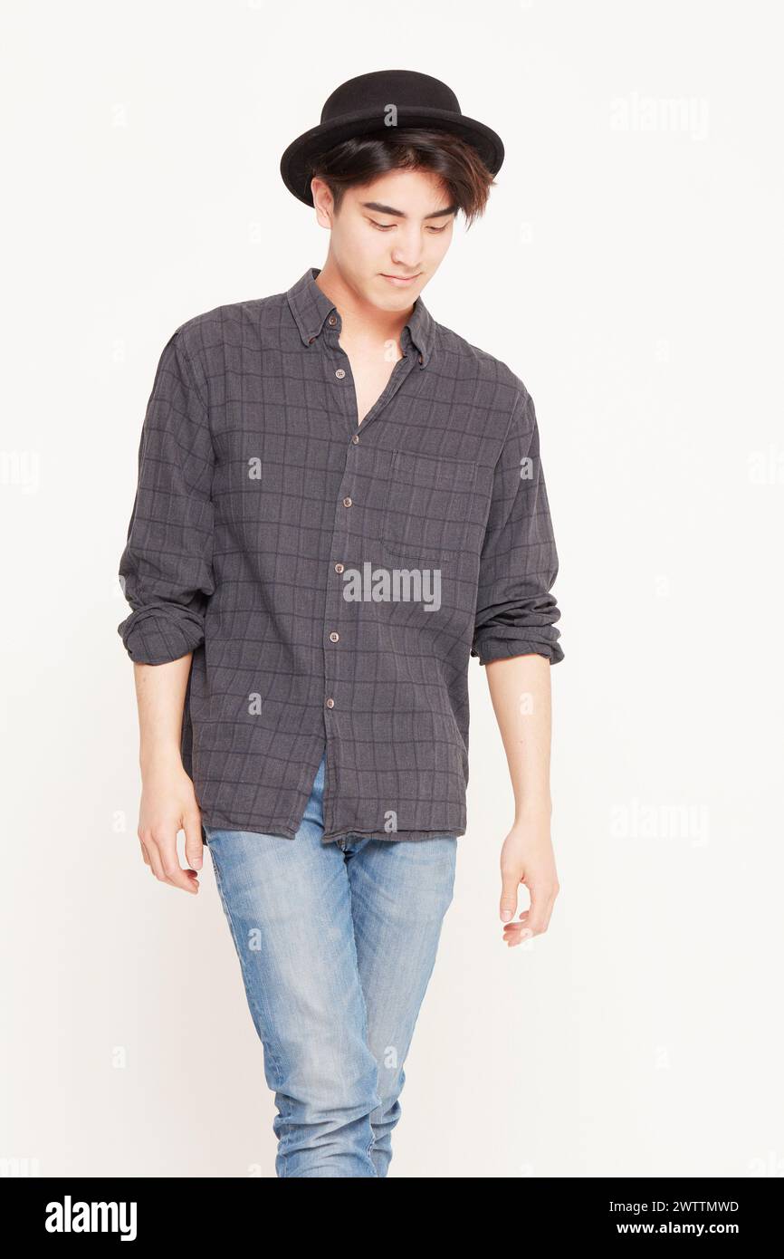 Giovane uomo elegante che posa in un abbigliamento casual con cappello Foto Stock