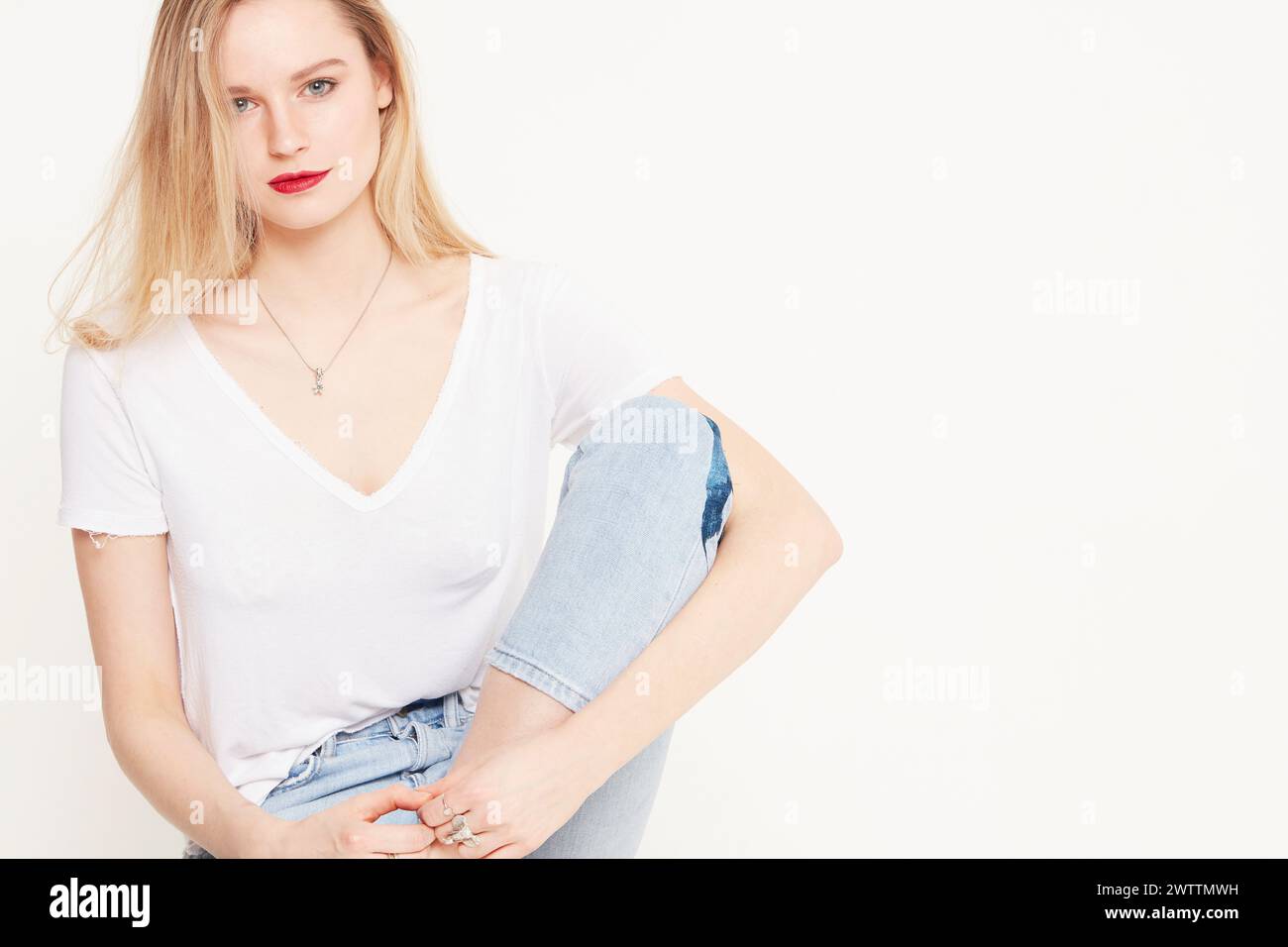 Donna in posa con una t-shirt bianca e jeans blu Foto Stock