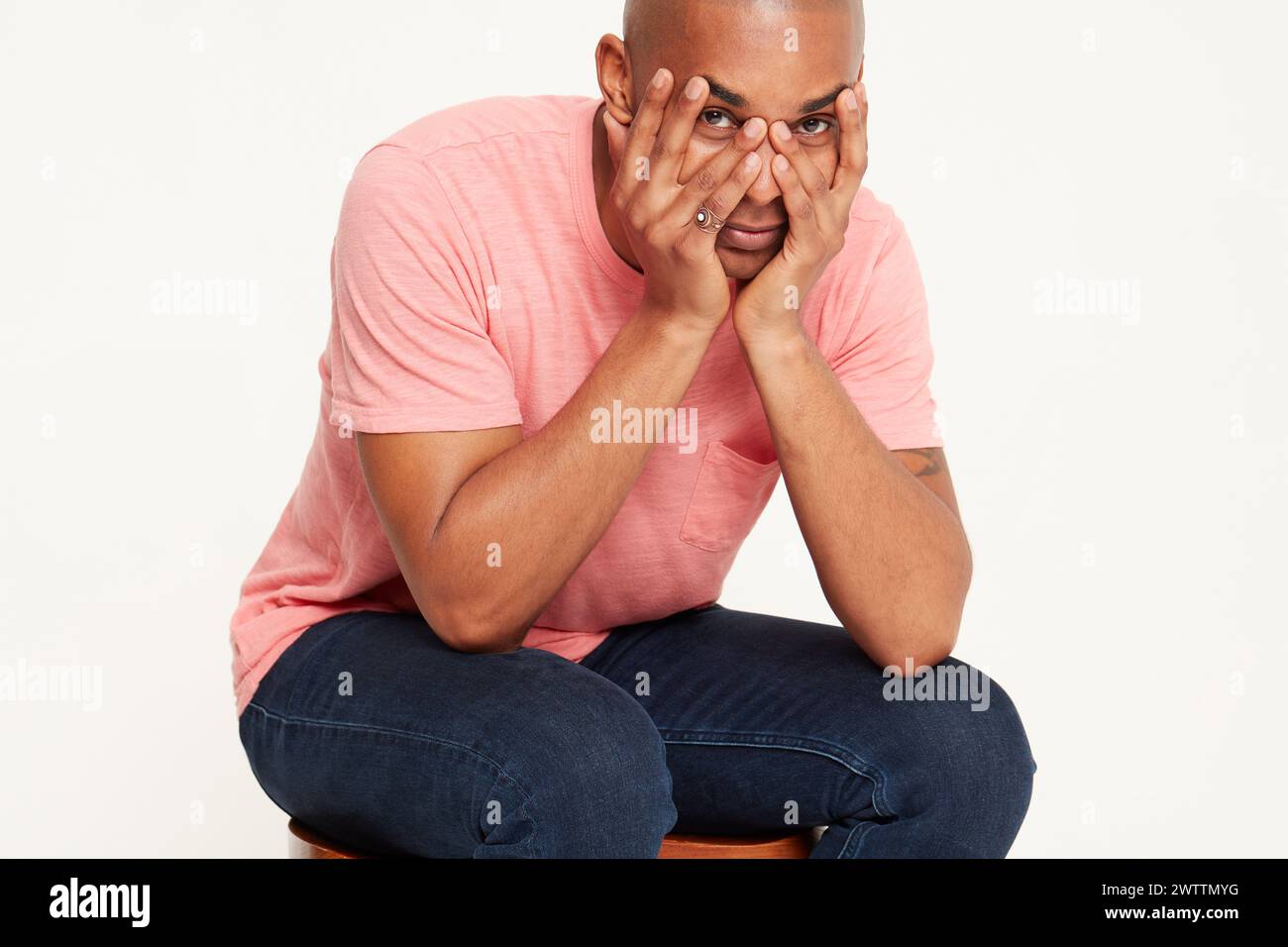 Uomo seduto sullo sgabello con le mani sul viso Foto Stock