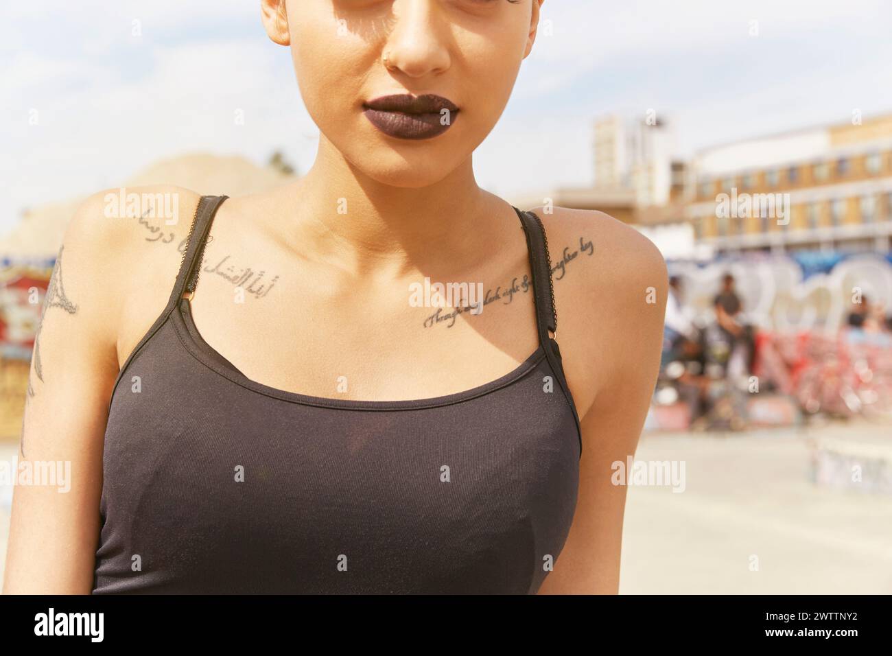 Donna con tatuaggi sotto un cielo soleggiato Foto Stock