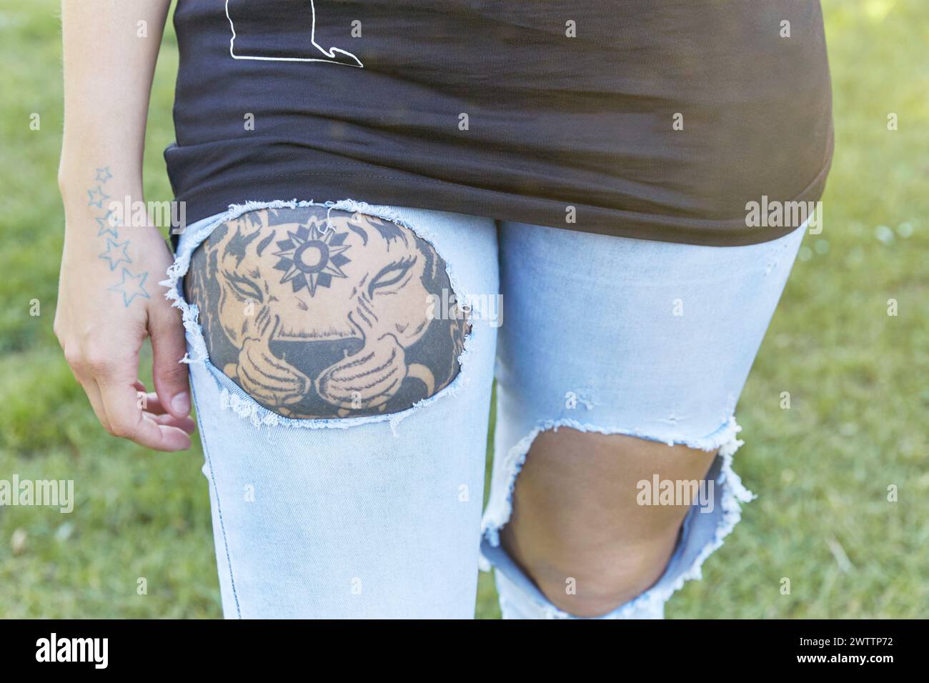 Persona con un tatuaggio che indossa jeans strappati Foto Stock