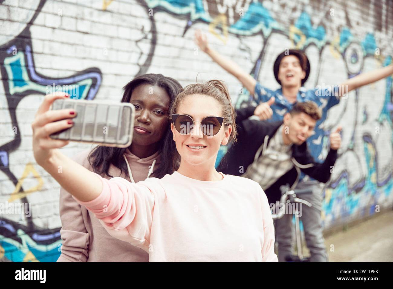 Amici che fanno un selfie contro il muro dei graffiti Foto Stock