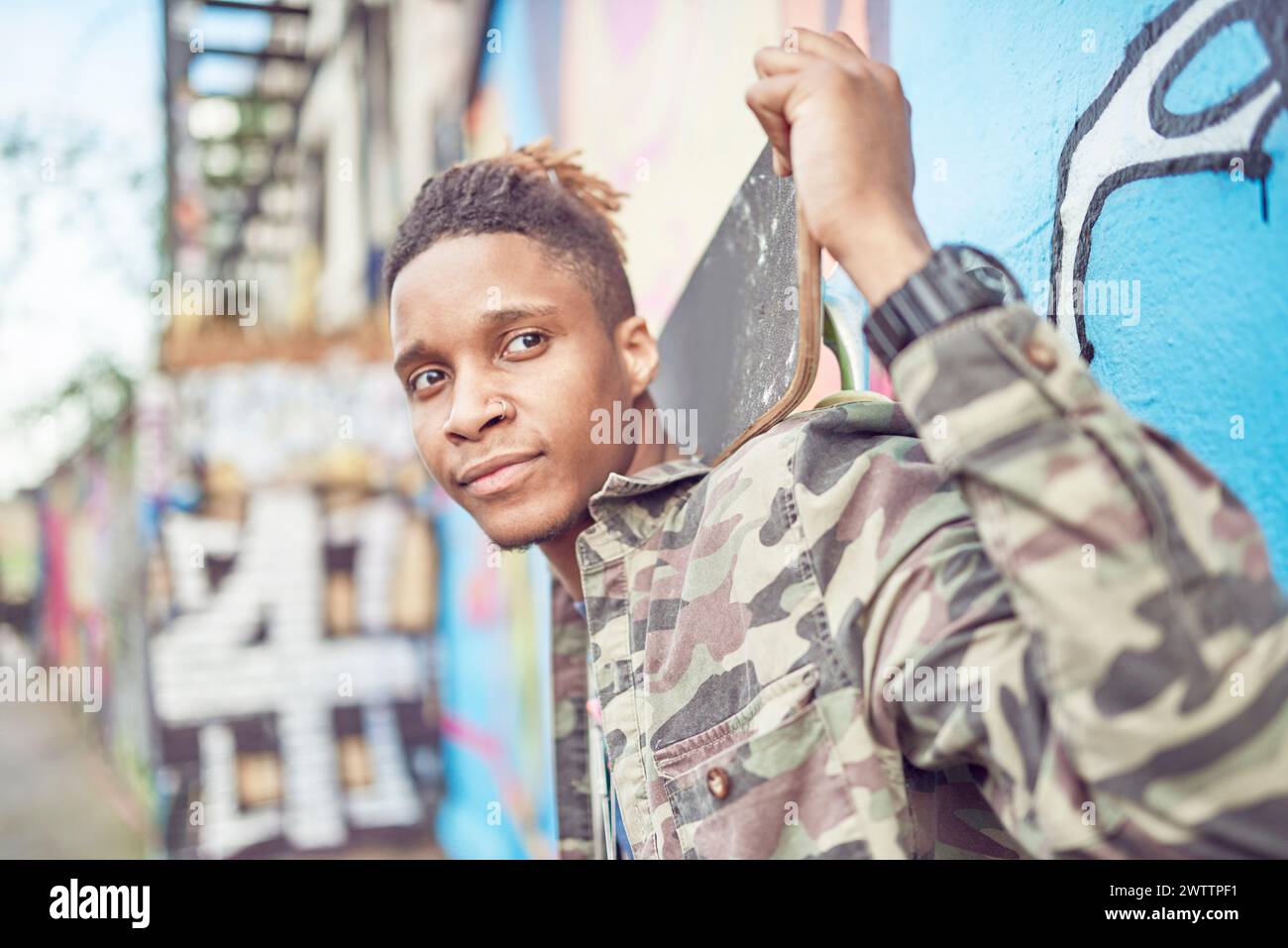 Uomo che posa di fronte a un muro di graffiti. Foto Stock