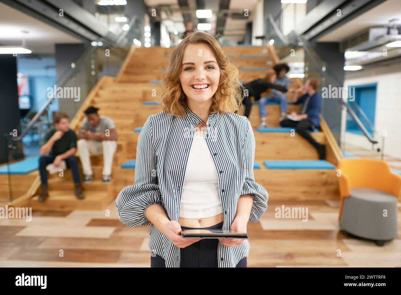 Donna sorridente che tiene un tablet in un ufficio moderno. Foto Stock