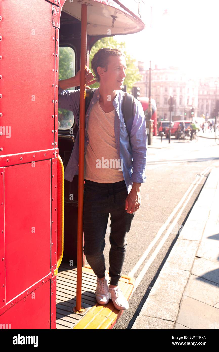 Persona che sale su un autobus rosso in una giornata di sole Foto Stock