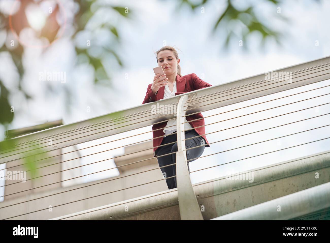 Donna appoggiata su una ringhiera del ponte da una vista ad angolo basso Foto Stock
