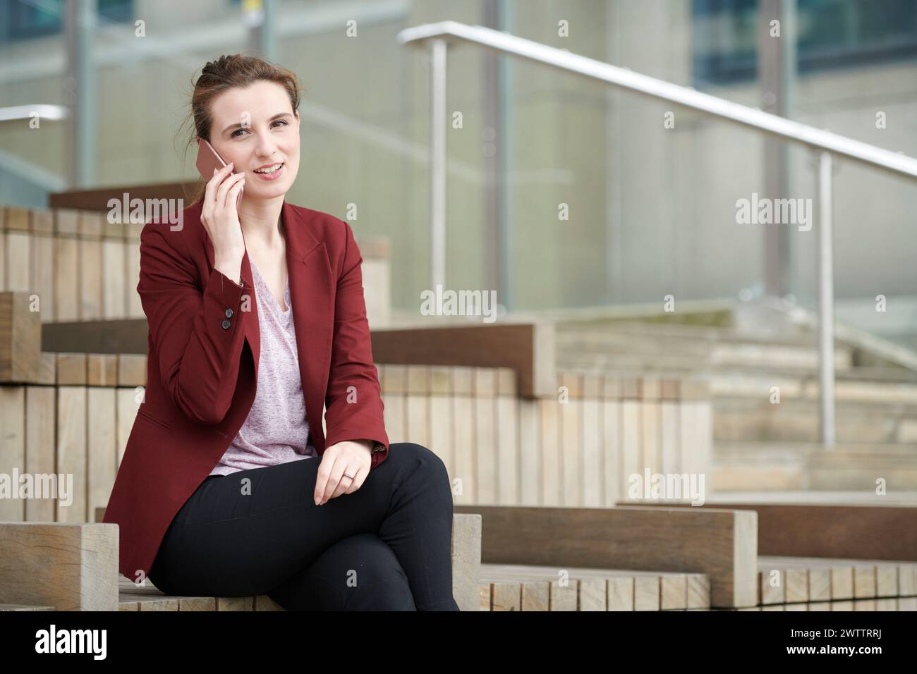 Donna che parla al telefono mentre è seduta sulle scale Foto Stock
