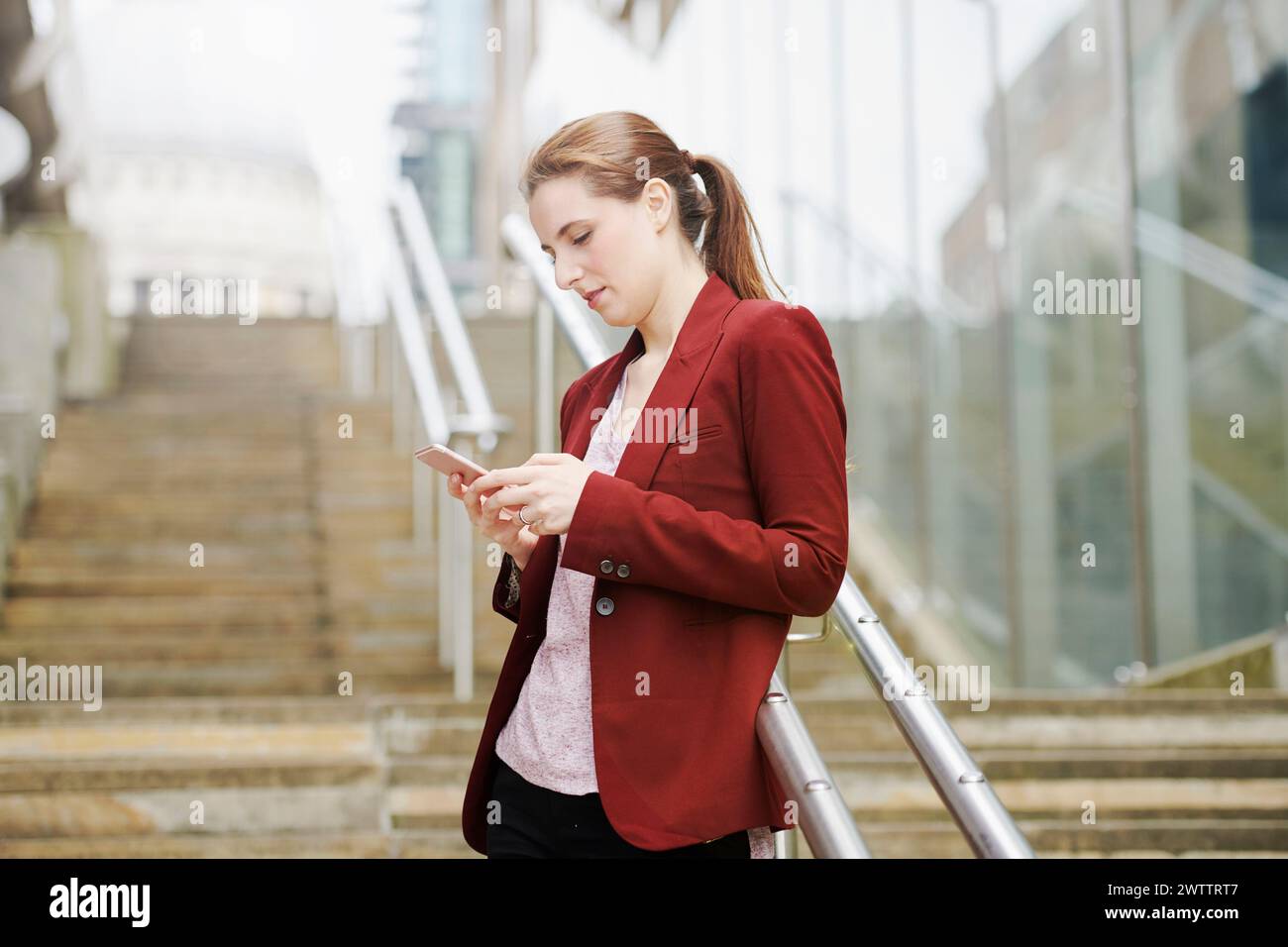 Donna che usa il telefono sulle scale della città Foto Stock