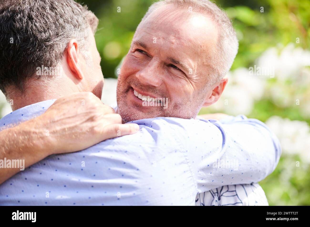Due uomini che abbracciano con sorrisi Foto Stock
