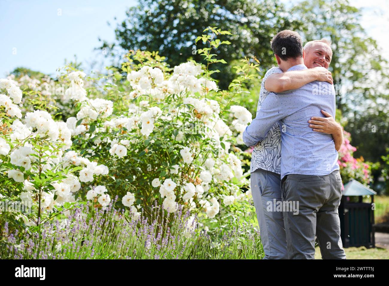 Due persone abbracciano un giardino fiorito Foto Stock