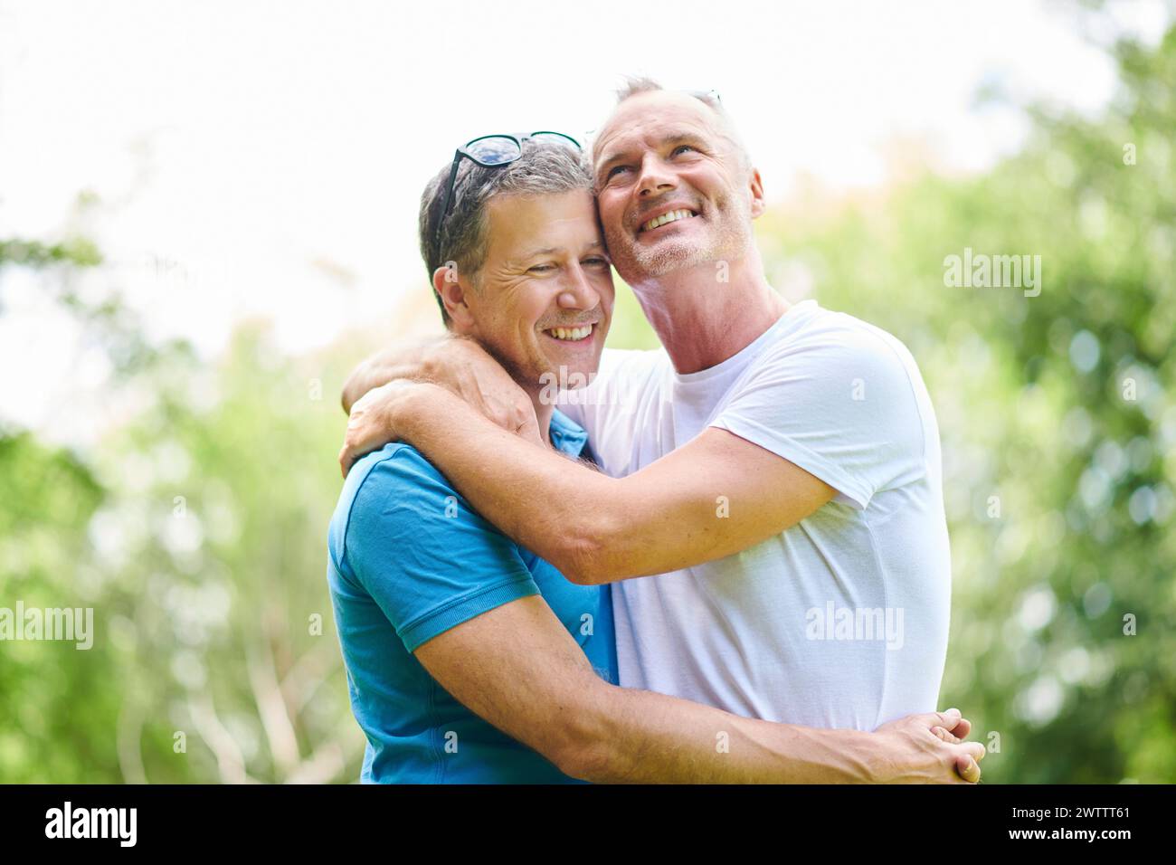 Due uomini che abbracciano e sorridono all'aperto Foto Stock