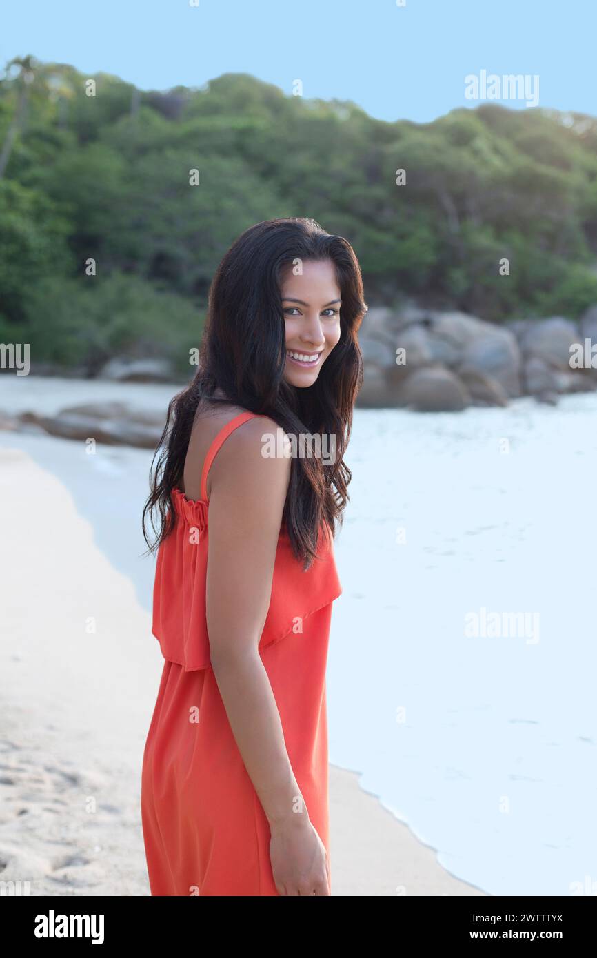 Donna in abito arancione su una spiaggia Foto Stock