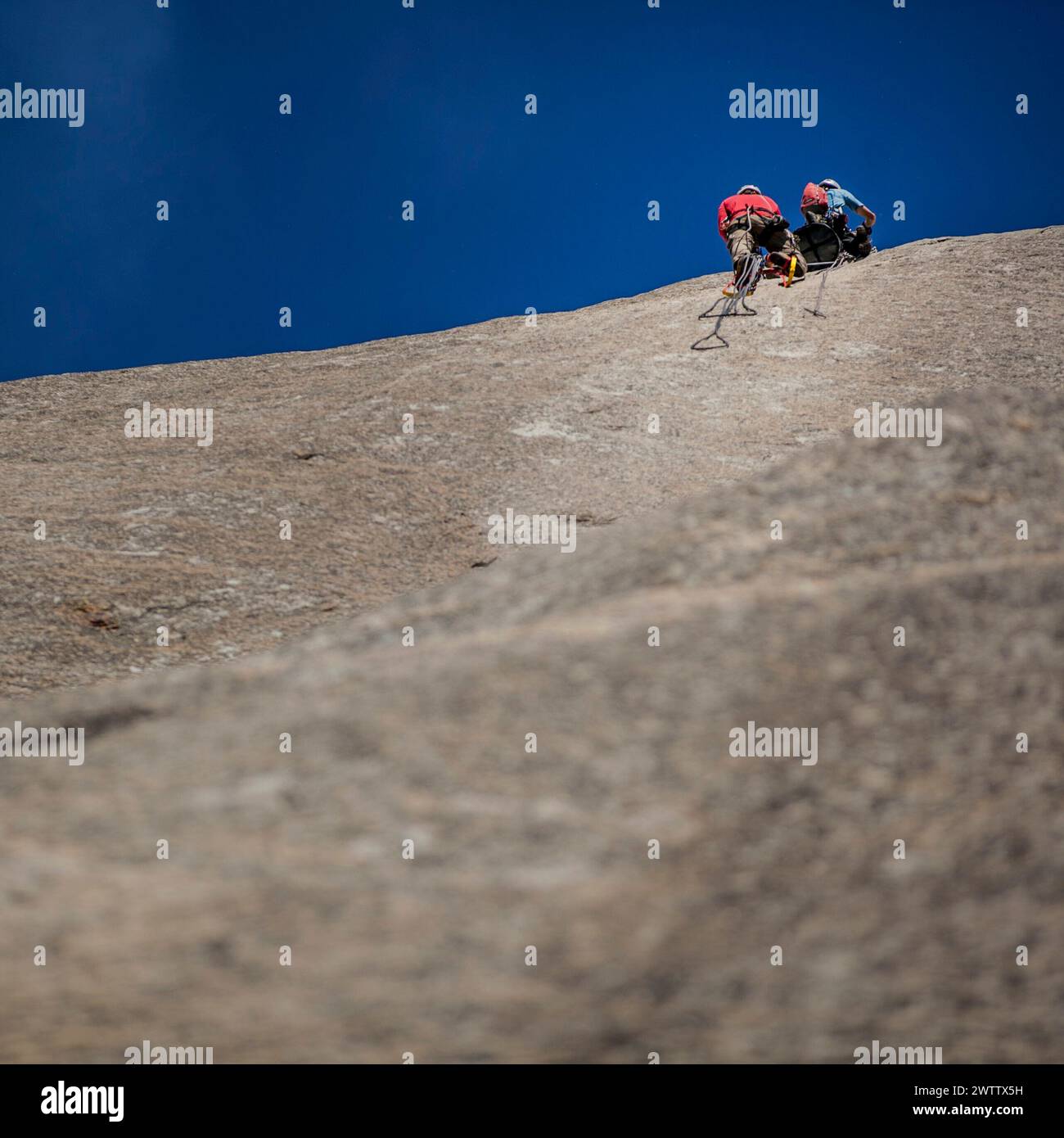 Scalatori che salgono su una ripida parete rocciosa Foto Stock