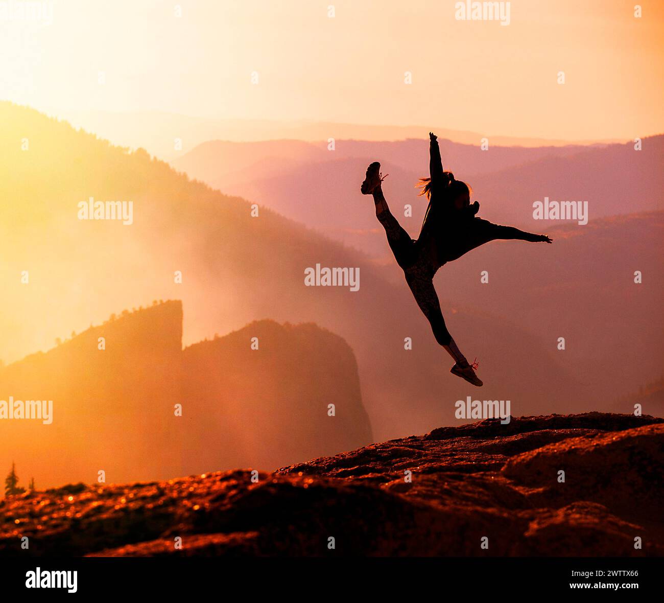 Silhouette di una ballerina che salta sullo sfondo di una montagna al tramonto Foto Stock