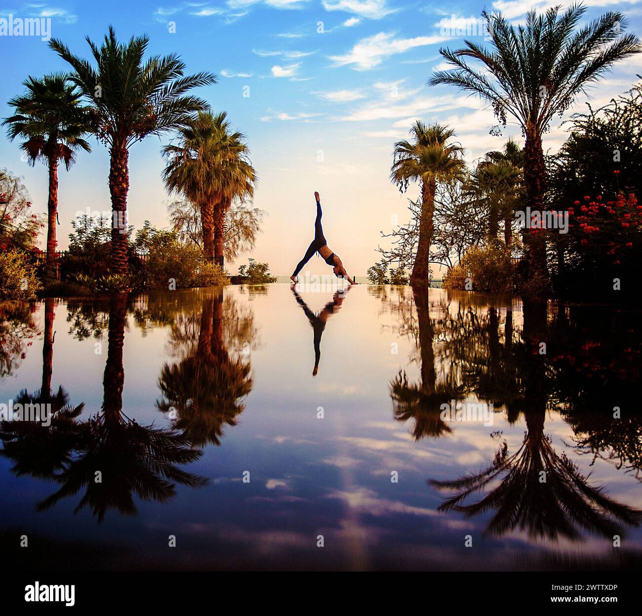 Persona che esegue una mano accanto a un corpo d'acqua riflettente al tramonto Foto Stock