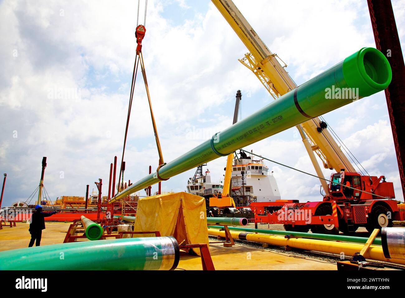 Gru per il sollevamento di tubi verdi in un sito industriale Foto Stock