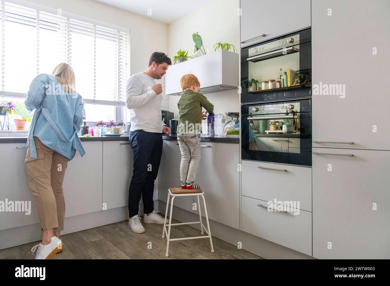La famiglia si diverte insieme in una cucina moderna. Foto Stock