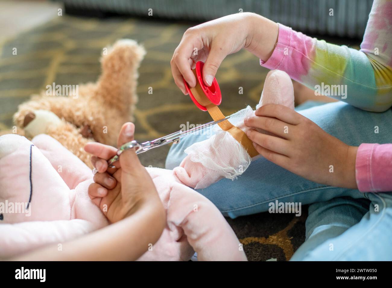 Un momento di nutrimento da bambino tende con cura alla benda sulla gamba di un animale imbottito Foto Stock