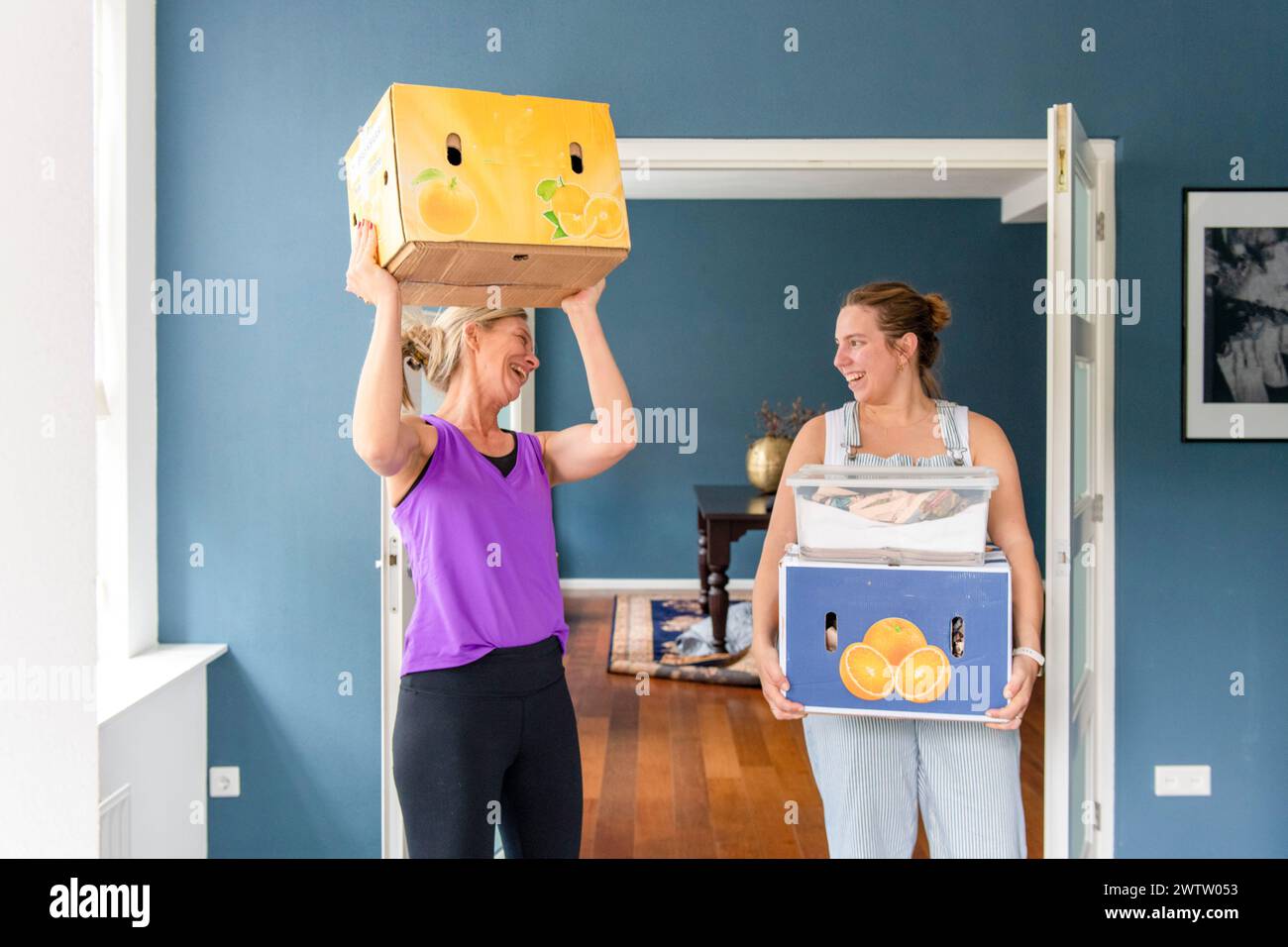 Due persone trasportano scatole decorate con stampe di frutta in una camera elegante. Foto Stock