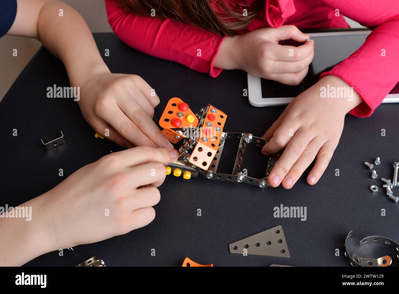 I bambini assemblano robot, mostrando abilità ingegneristiche. Vista dall'alto verso il basso della tabella. Concetto di istruzione, creatività e apprendimento pratico Foto Stock