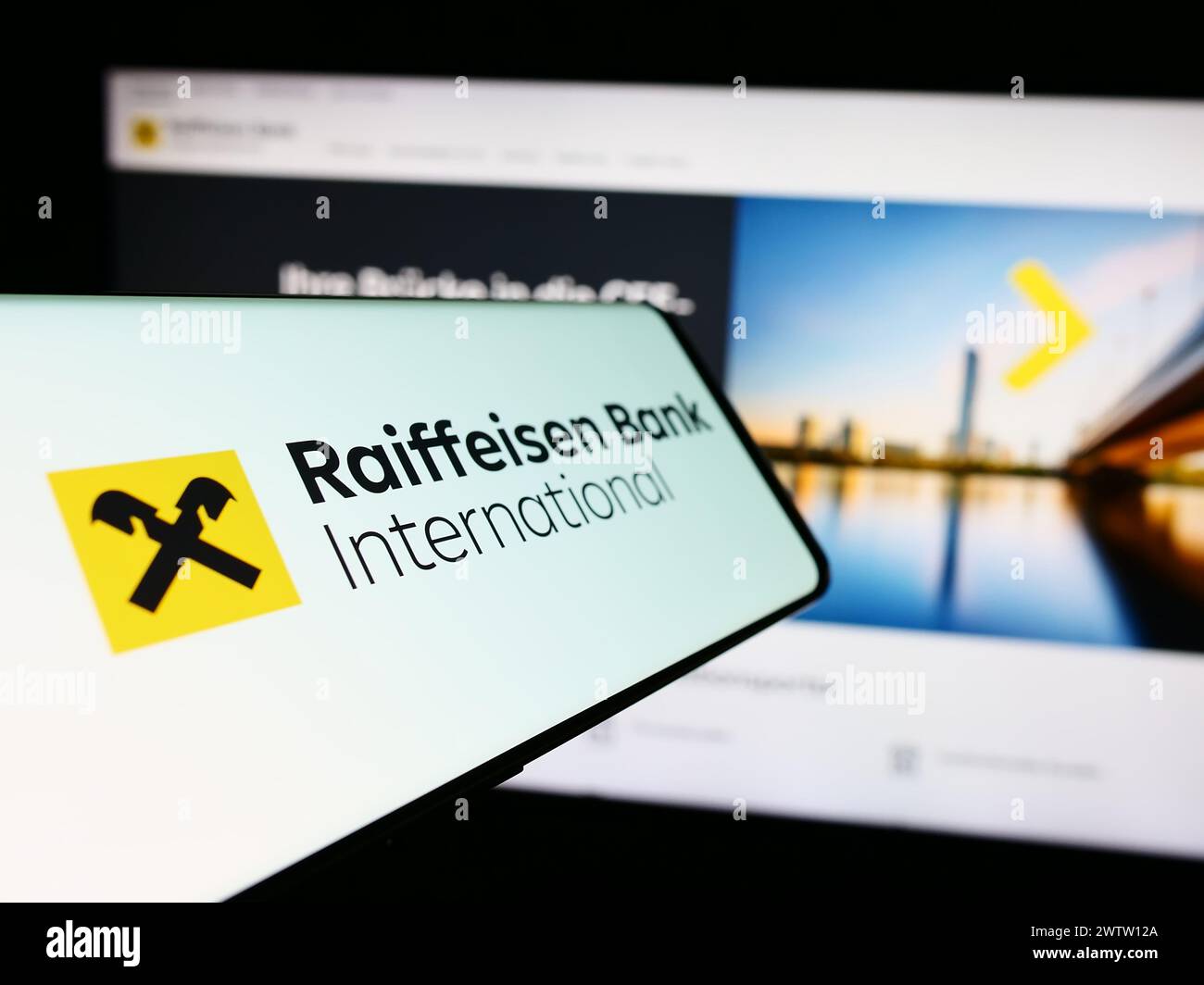 Smartphone con logo della società austriaca Raiffeisen Bank International AG (RBI) davanti al sito Web. Mettere a fuoco la parte centrale sinistra del display del telefono. Foto Stock