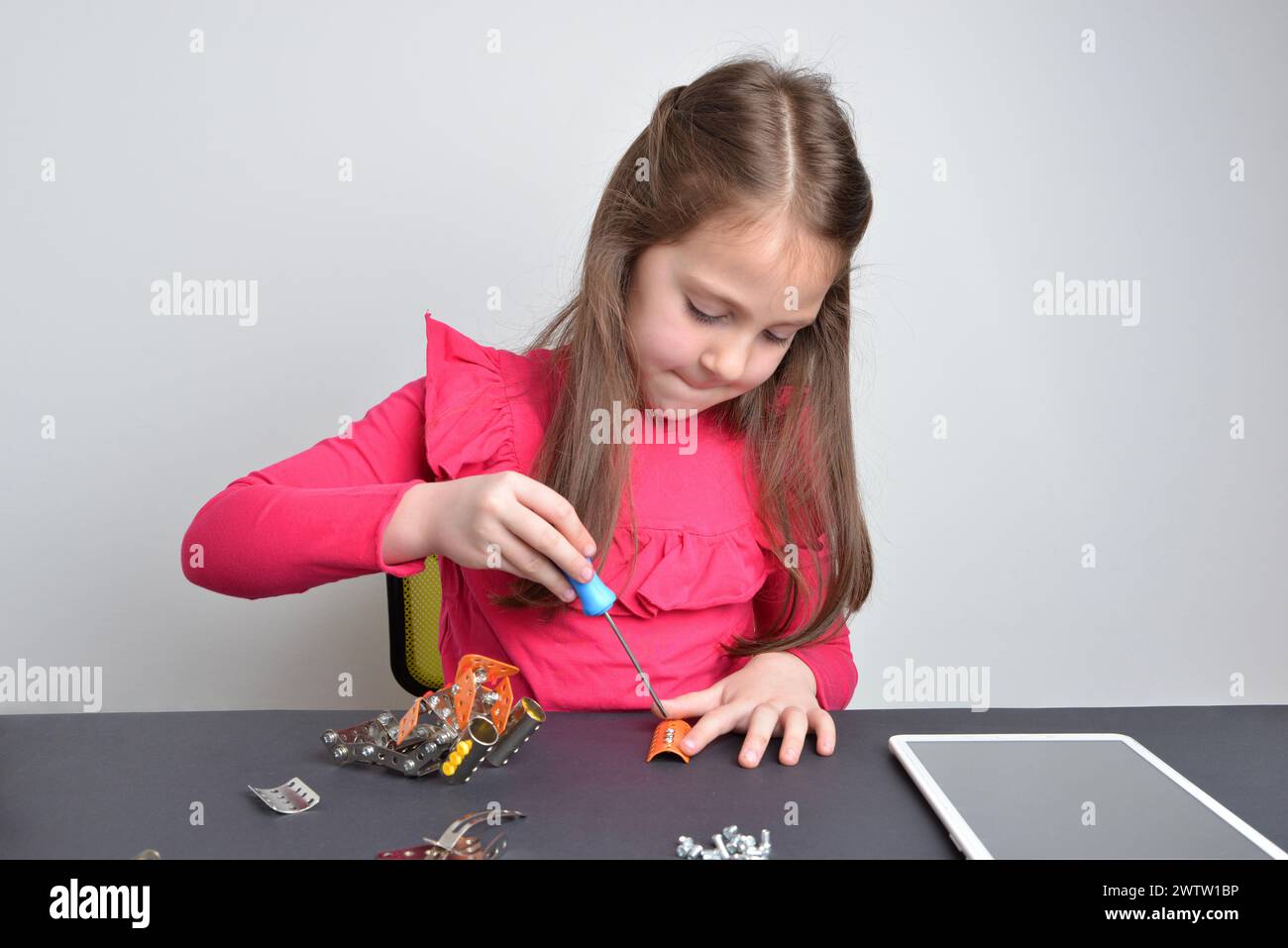 La bambina fissa parti metalliche su un robot. Concetto di apprendimento pratico, istruzione, creatività ed esplorazione ingegneristica Foto Stock