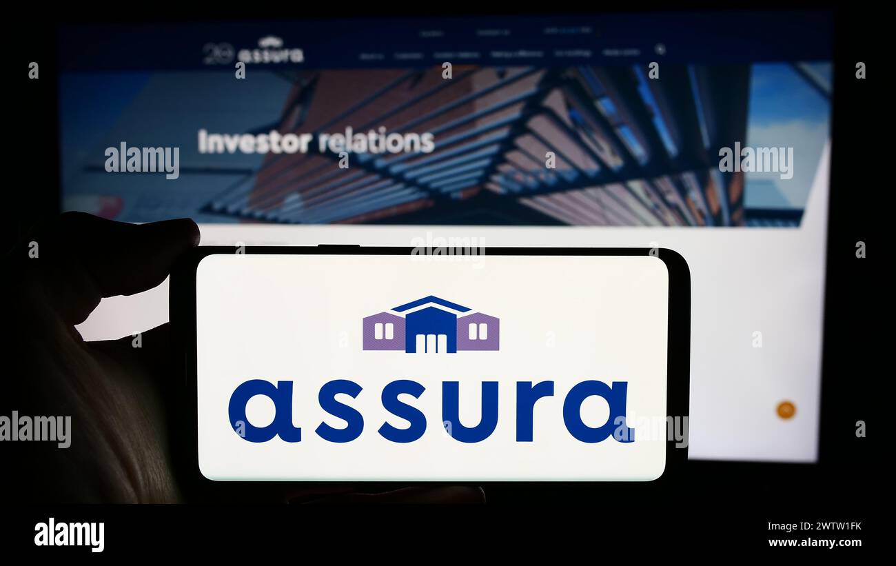 Persona che detiene cellulare con logo della società immobiliare sanitaria britannica assicurazione plc di fronte alla pagina web aziendale. Mettere a fuoco il display del telefono. Foto Stock