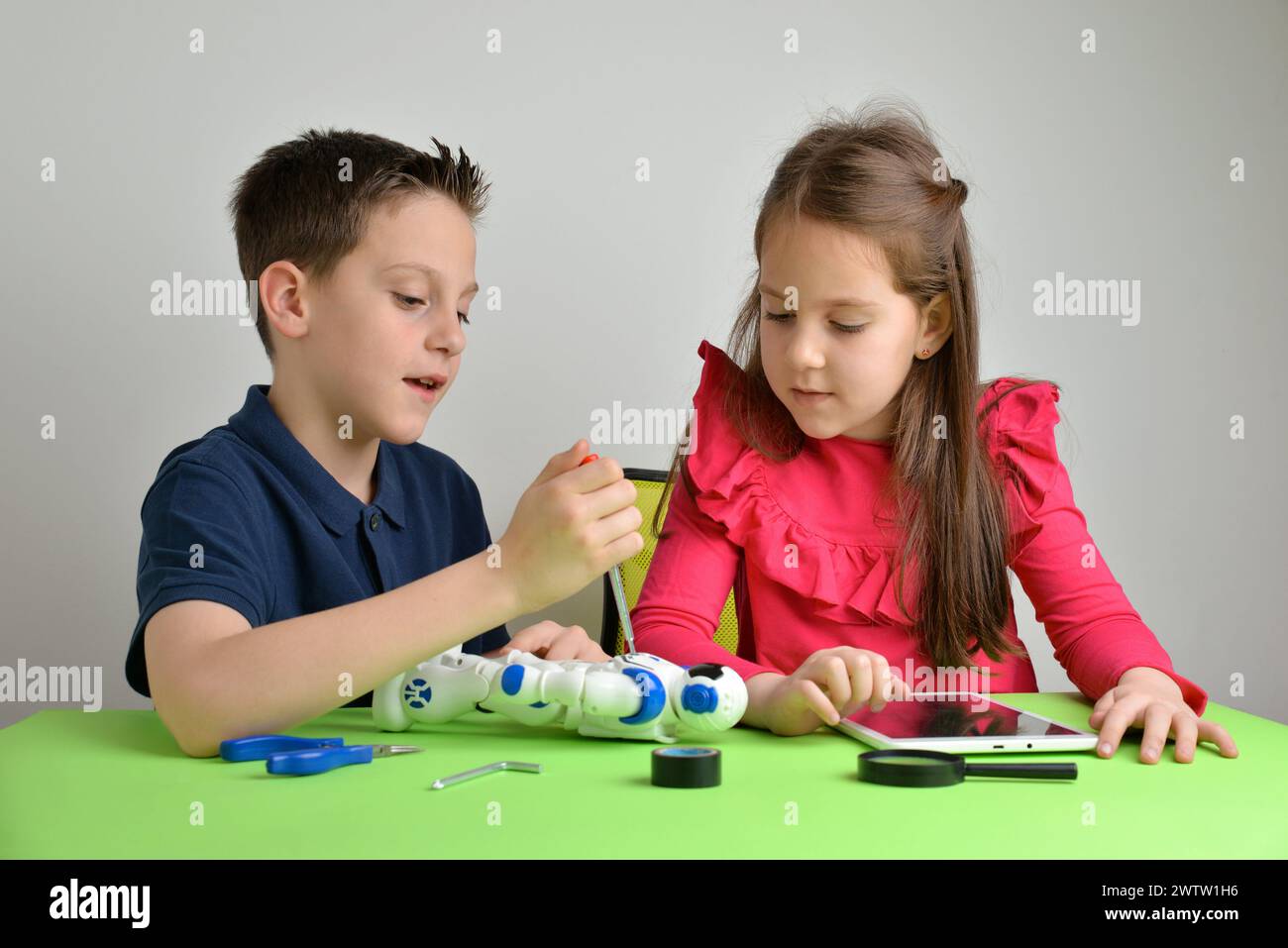 I bambini assemblano il robot sul tavolo di lavoro, impegnandosi in una conversazione. Concetto di lavoro di squadra, collaborazione, istruzione ed esperienza pratica di apprendimento Foto Stock