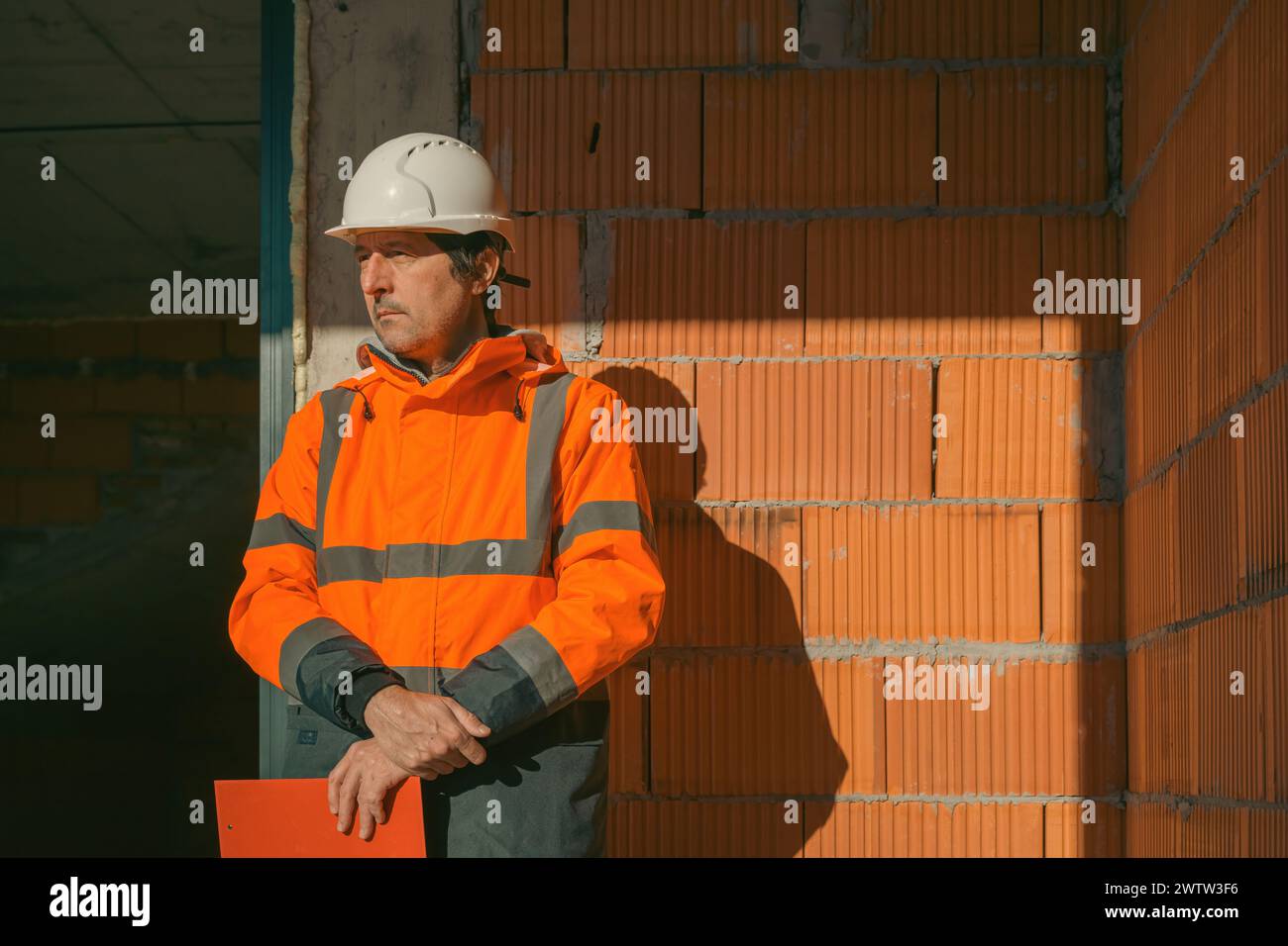 Ritratto dell'ingegnere edile sul cantiere, appoggiato a un muro incompiuto Foto Stock