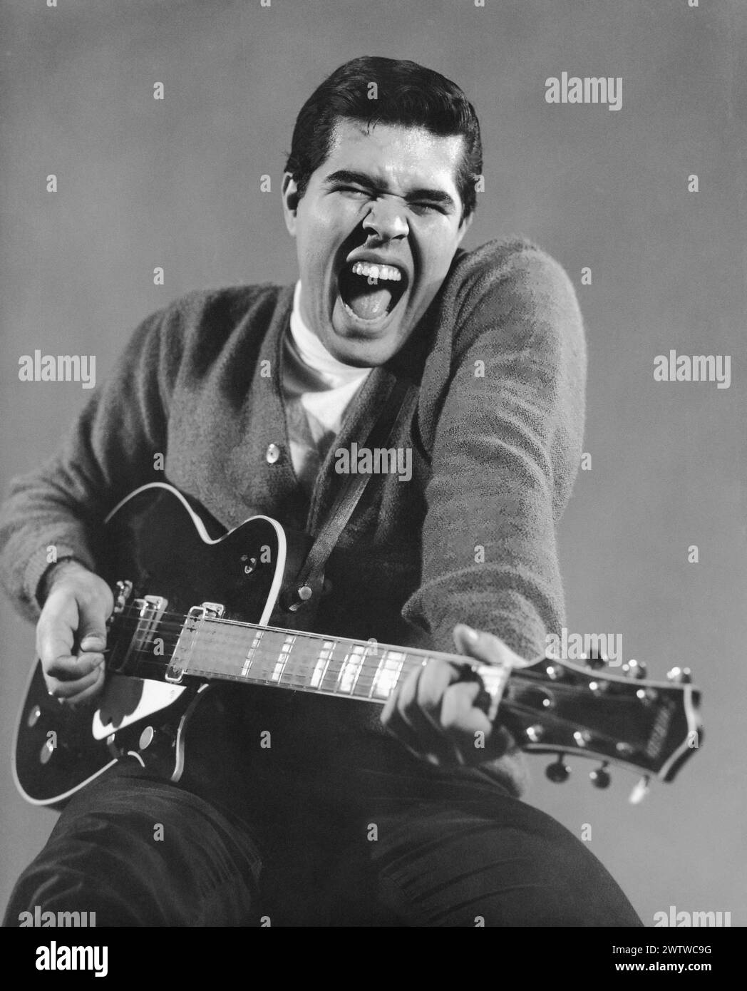 Uomo di mezza età che canta mentre suona la chitarra Foto Stock