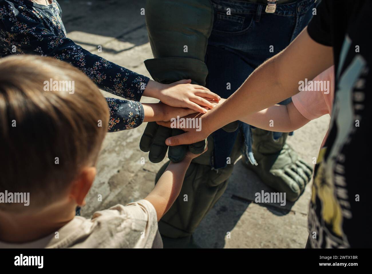 Un gruppo di persone diverse in cerchio, che si tengono per mano e mostrano unità e solidarietà. Foto Stock