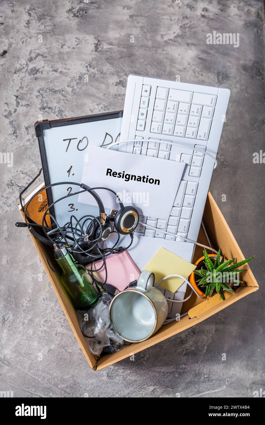 Lettera di dimissioni e scatola di cartone con tastiera, strumenti da ufficio e accessori personali Foto Stock