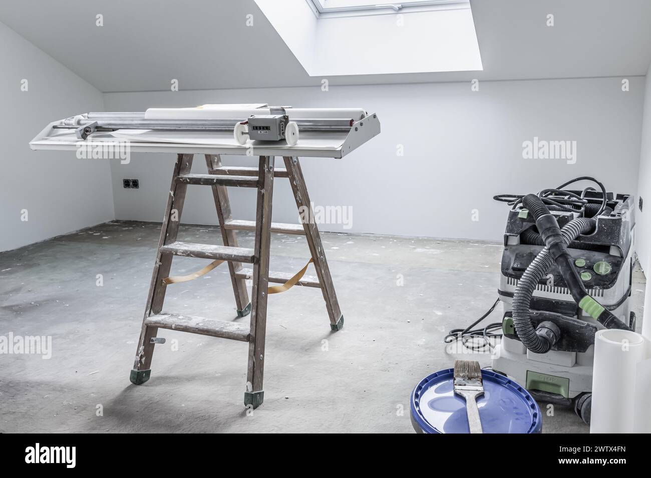 Ristrutturazione della casa - camera vuota con tavolo incollato per tagliare carta da parati e utensili Foto Stock