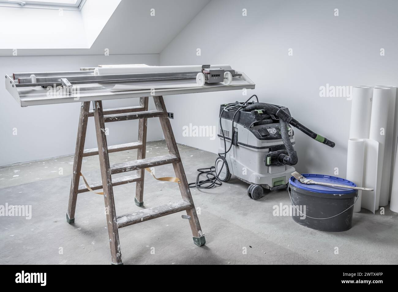 Ristrutturazione della casa - camera vuota con tavolo incollato per tagliare carta da parati e utensili Foto Stock