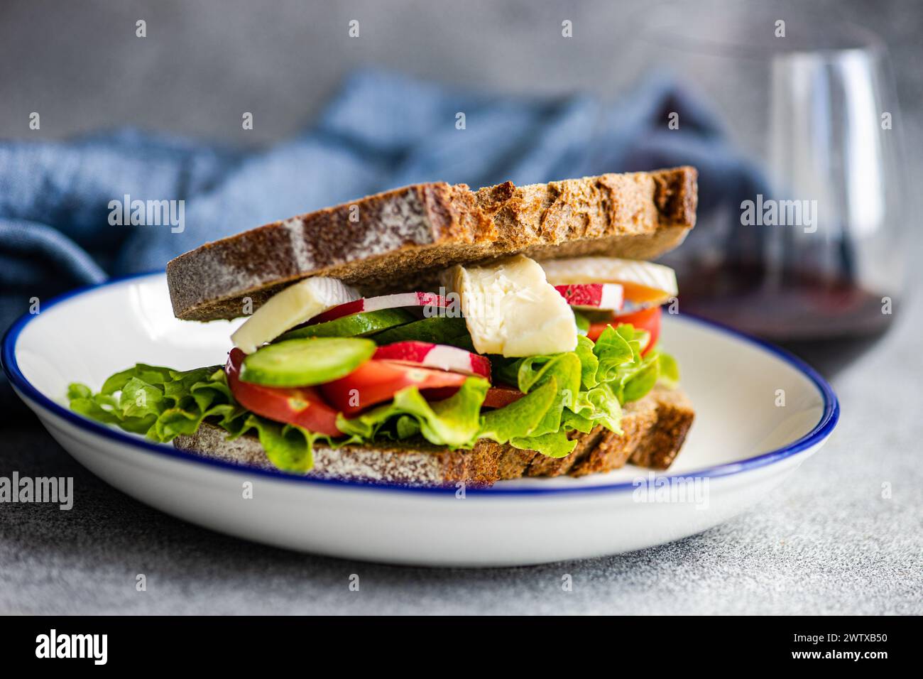 Primo piano di un panino di pane di segale con lattuga, pomodoro, cetriolo, ravanello e formaggio brie Foto Stock