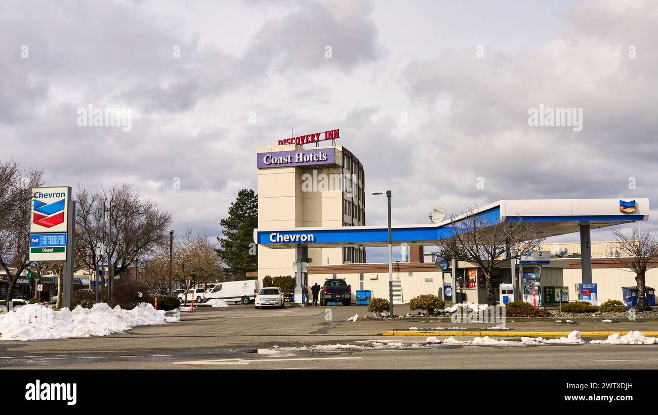 Veicoli che si riforniscono di carburante in un angolo della stazione di servizio Chevron con un hotel sullo sfondo. Foto Stock
