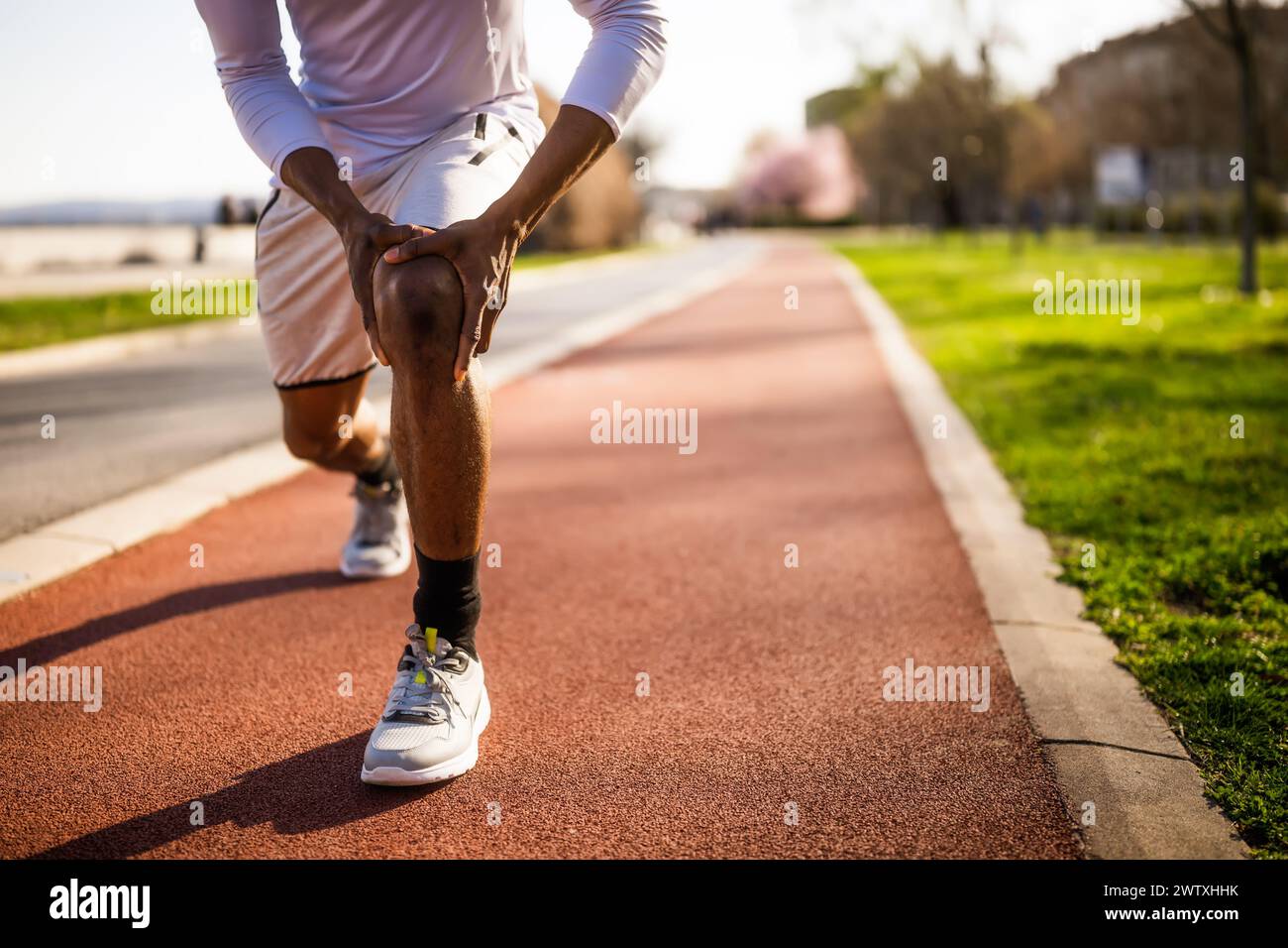 Il giovane afroamericano è ferito mentre fa jogging. Ha dolore al ginocchio. Foto Stock