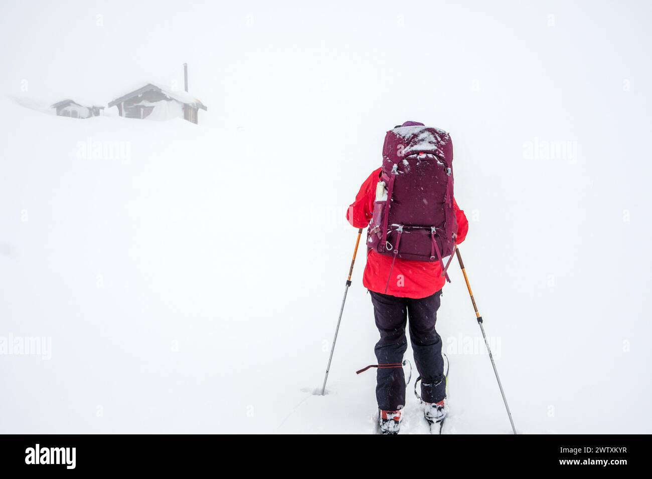 Una sciatrice che si dirige verso una cabina di montagna in scarsa visibilità, Jotunheim, Norvegia Foto Stock