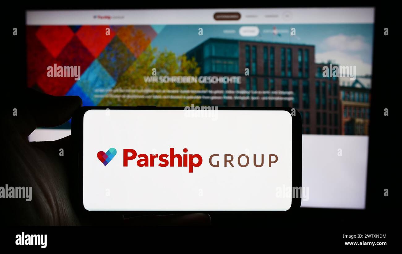 Persona che detiene un cellulare con il logo della società tedesca di incontri online ParshipMeet Holding GmbH davanti alla pagina web aziendale. Mettere a fuoco il display del telefono. Foto Stock