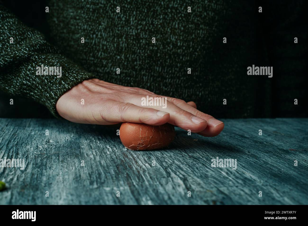 primo piano di un uomo che lancia un uovo sodo contro il tavolo per toglierne il guscio Foto Stock