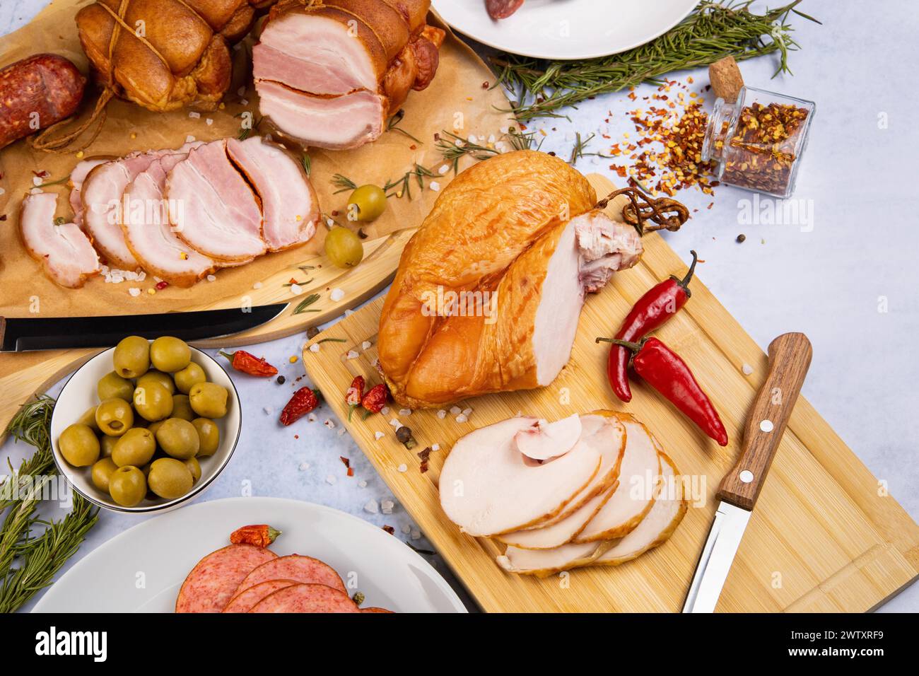 abbondanza di prelibatezze di carne su uno sfondo di cemento circondato da varie spezie ed erbe aromatiche, olive, peperoni Foto Stock