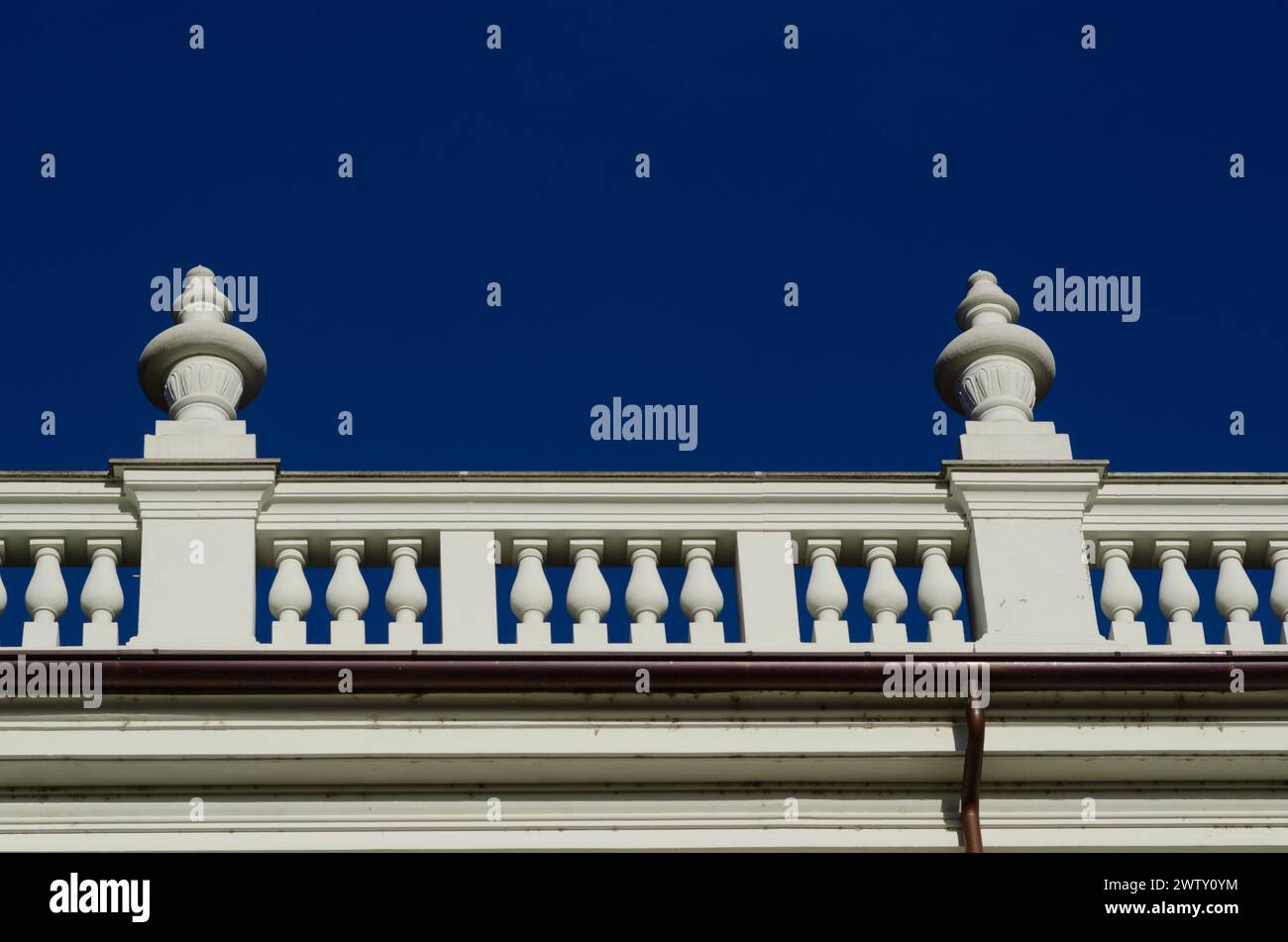 particolare di un elegante palazzo nobiliare, con elementi neoclassici di balaustra sul cono con colonne sulla facciata. sfondo al cielo blu intenso. Foto Stock