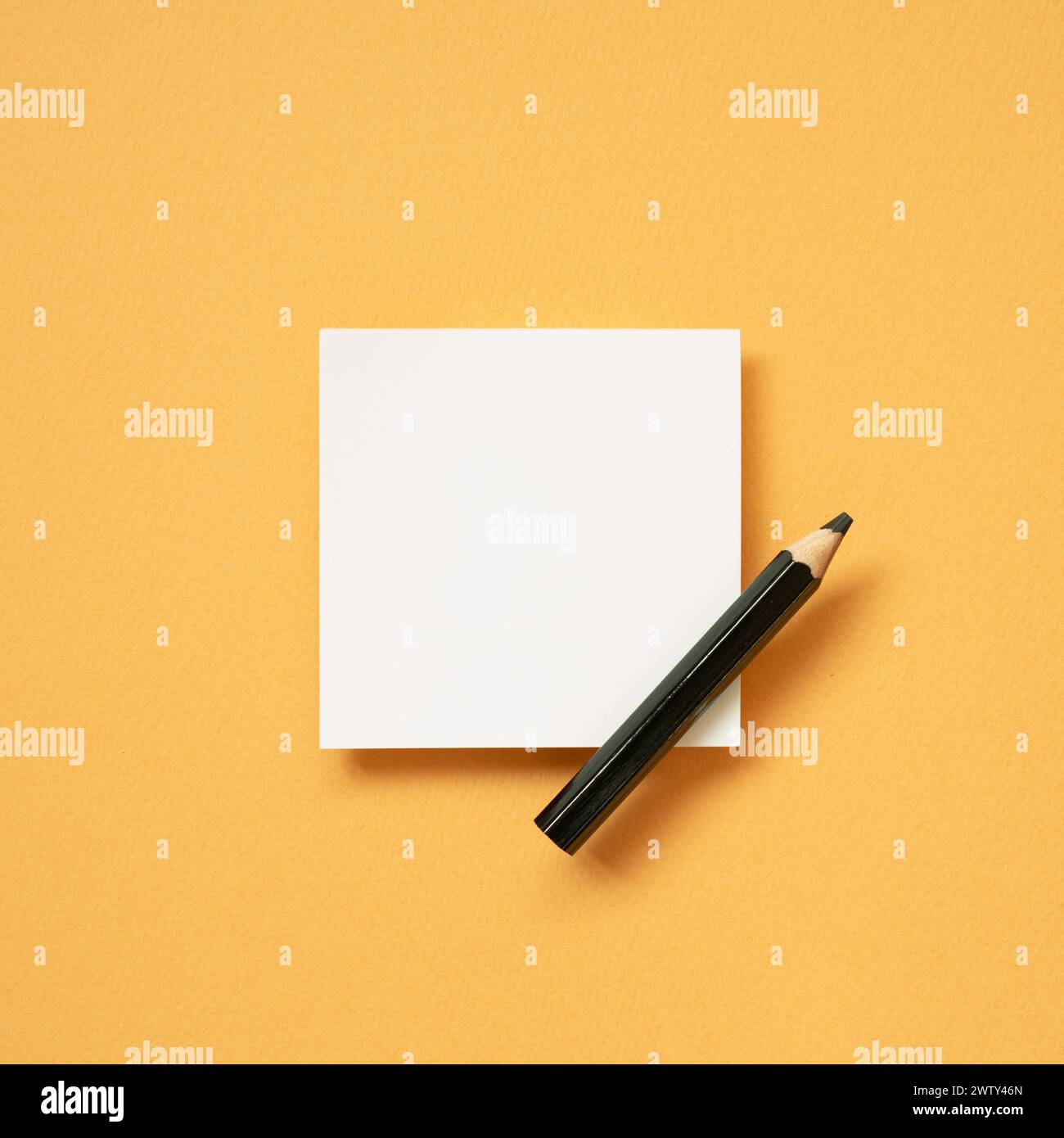 Blocco note bianco vuoto e matita su sfondo arancione della scrivania. vista dall'alto, copia spazio Foto Stock