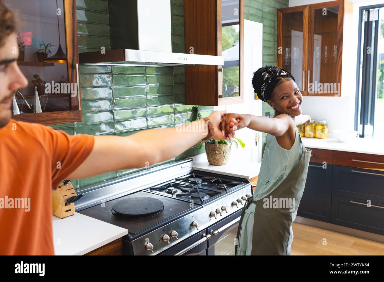 Una coppia variegata che balla e si diverte in cucina a casa Foto Stock