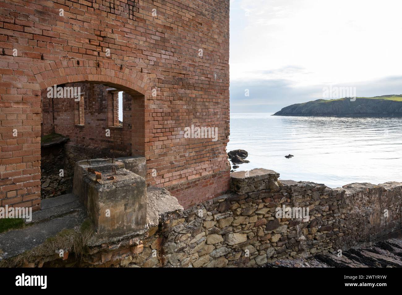 Resti di una vecchia fabbrica di mattoni abbandonata a Porth Wen, sulla costa settentrionale di Anglesey, nel Galles del Nord. Foto Stock